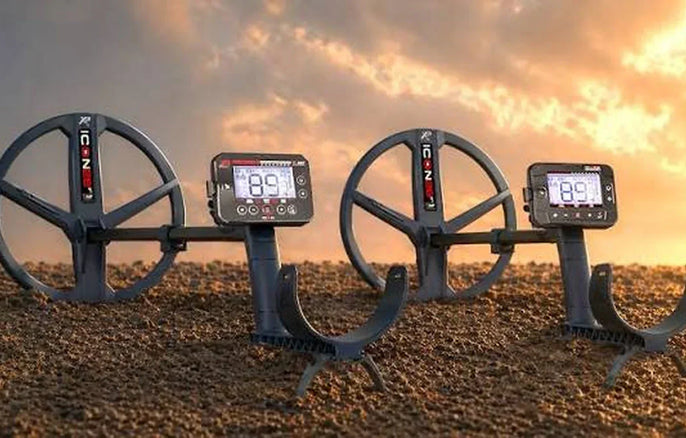 Détecteurs de métaux XP ICON et XP ICON X présentés côte à côte sur fond de terrain avec lumière de coucher de soleil.